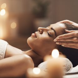 Attractive african girl enjoying face massage in spa salon. Closed eyes.